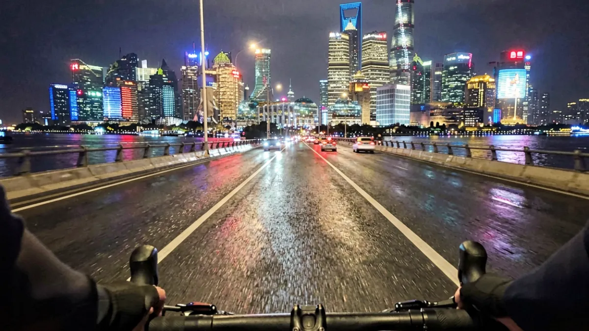 骑行者视角拍摄的上海外滩夜景，灯光倒映在黄浦江水面